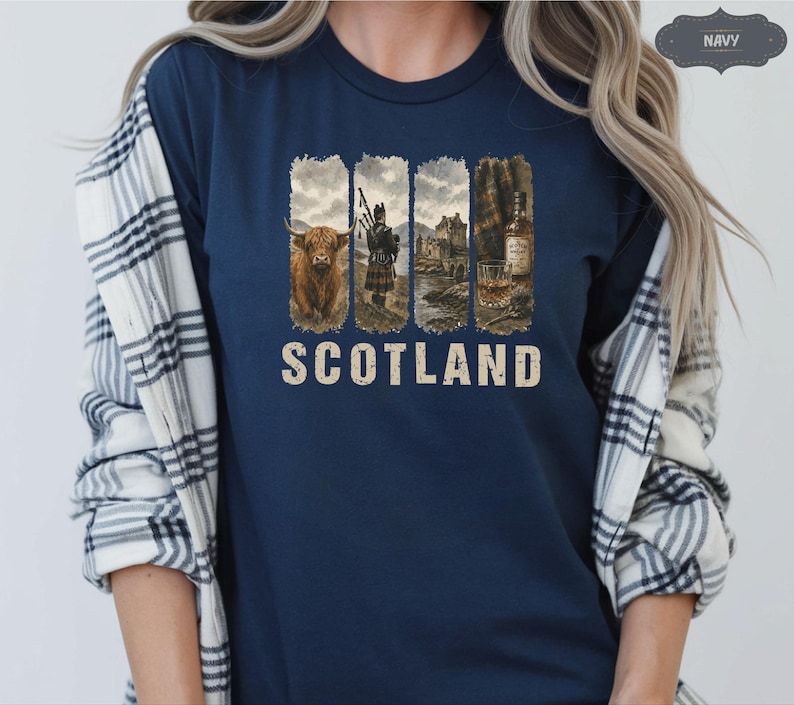 May include: Navy blue t-shirt featuring a distressed graphic with images of a Highland cow, a bagpiper, a castle, and a whiskey bottle. The word "SCOTLAND" is printed in a vintage font below the images. The shirt is a solid navy color.