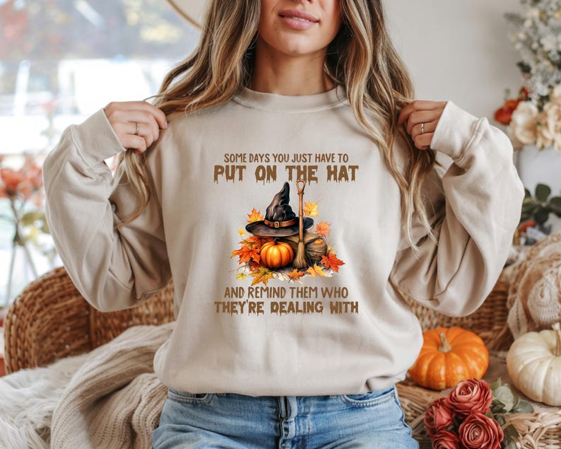 Funny Halloween witch hat sweatshirt and t-shirt design with broom, pumpkin, autumn leaves and quote 'Some days you just have to put on the hat and remind them who they're dealing with' – cozy fall clothing for kids and adults, perfect spooky season outfit gift.