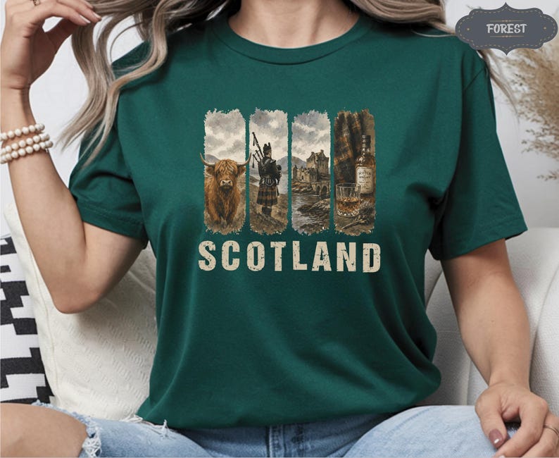 May include: Dark green t-shirt featuring a graphic design with the word "SCOTLAND" in a distressed font. The design includes images of a Highland cow, a bagpiper, a castle, and a whiskey bottle and glass. The shirt is made of a soft material.