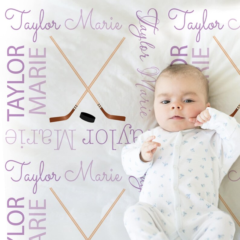 A baby lying on a blanket with the names "Taylor" written on it in purple text.