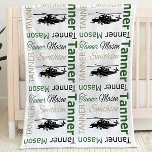 May include: White baby blanket with a repeating pattern of black helicopter silhouettes and the name "Tanner Mason Smithson" in various fonts and colors, including green and gray.