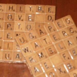 May include: A set of two coasters made from wooden tiles with letters spelling out the words "LOVE" and "GATE" in a brown and white color scheme.