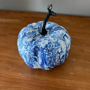 May include: A blue and white patterned fabric pumpkin with a black metal stem.