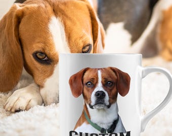 May include: White ceramic mug featuring a dog portrait with brown and white fur, a green collar, and the word "CUSTOM" in black. A second dog is visible in the background.