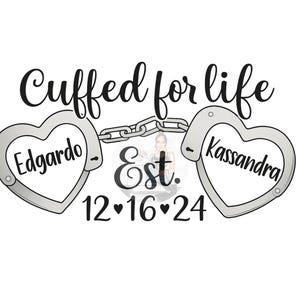 Puede incluir: Diseño gráfico con esposas en forma de corazón conectadas por una cadena. El texto "Cuffed for life" se arquea sobre las esposas. Los nombres "Edgardo" y "Kassandra" están dentro de las esposas en forma de corazón, con la fecha "12•16•24" debajo.