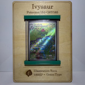 May include: A framed Ivysaur Pokemon card. The card is in a clear plastic holder, set against a wooden frame with green accents. Text on the frame reads "Ivysaur" and "Pokemon 151 • 167/165". The card is an Illustration Rare, 100HP, Grass Type.