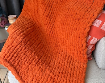 Coperta a maglia grossa: morbida coperta artigianale color arancio bruciato per un arredamento accogliente.