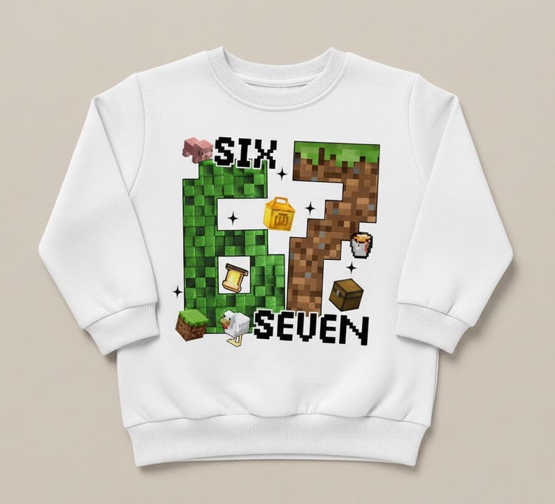 May include: White sweatshirt with a pixelated "6" and "7" design. The "6" is green and the "7" is brown, with various pixelated images of a pig, chicken, chest, and other objects. The word "SIX" is above the "6" and "SEVEN" is below the "7".