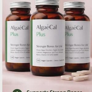 May include: Three amber glass bottles of AlgaeCal Plus dietary supplements with white labels featuring green accents. Each label displays the text AlgaeCal Plus, Stronger Bones for Life, and 120 Veggie Capsules. Several beige capsules lie in front.