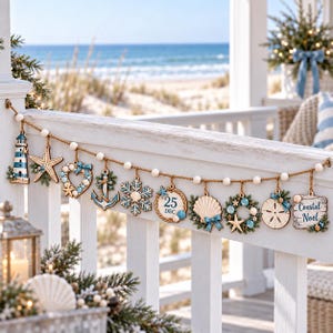 May include: A decorative garland featuring a series of hanging ornaments including a lighthouse, starfish, heart, anchor, snowflake, a circular sign reading 25 DEC, seashell, wreath, sand dollar, and a square sign reading Coastal Noel.