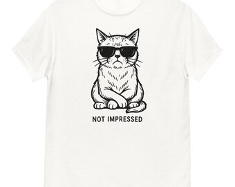 May include: White t-shirt with a black and white drawing of a cat wearing sunglasses. The cat is sitting with its paws crossed and the text "NOT IMPRESSED" is below the image.