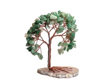 May include: A decorative tree sculpture with a copper wire trunk and branches, adorned with green gemstone leaves. The tree sits on a natural, light-colored stone base. The overall design is a unique blend of natural elements and craftsmanship.