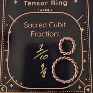 May include: A beige drawstring bag with a black card featuring the text "Sacred Cubit Tensor Ring" and two copper-colored rings. The card also displays "Sacred Cubit Fraction" and the Etsy shop URL.