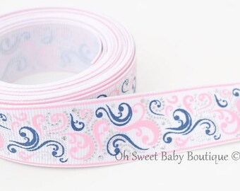 May include: White satin ribbon with a pink and blue swirl pattern and silver glitter accents. The ribbon is rolled up and the pattern is visible on the edge.