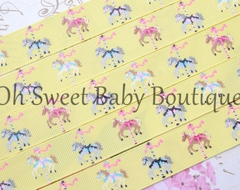 May include: Yellow ribbon with a repeating pattern of carousel horses in various colors. The ribbon is made of grosgrain and has a subtle sheen. The text "Oh Sweet Baby Boutique" is printed on the ribbon.