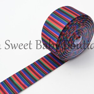 May include: A roll of colorful striped ribbon with red, blue, green, and orange stripes. The ribbon is rolled up and the end is hanging down.