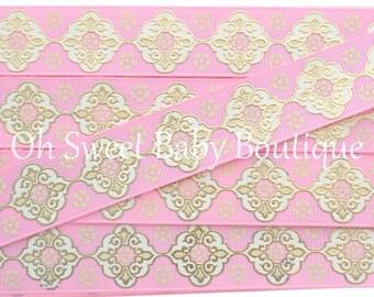 May include: Pink and gold ribbon with a repeating pattern of white and gold ornate squares. The ribbon is folded in layers to show the pattern.