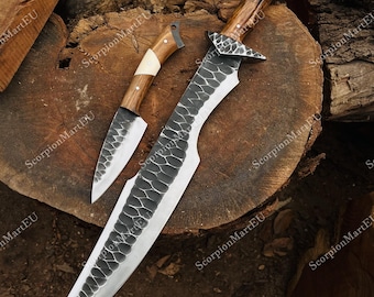 May include: Two handmade knives with wooden handles and textured blades. The larger knife has a curved blade and a decorative metal guard. The smaller knife is a matching set. The blades have a unique pattern.
