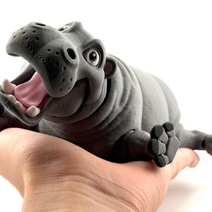 K&ouml;nnte beinhalten: Eine wei&szlig;e Keramik-Tasse mit schwarzem Henkel und dem Text "But First, Coffee" in fetter, schwarzer Schrift. Die Tasse steht vor einem neutralen Hintergrund, der ihr schlichtes Design hervorhebt.