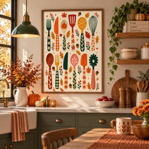 May include: A framed wall art print featuring a colourful illustration of various kitchen utensils like spoons, forks, knives, and whisks, decorated with autumn-themed patterns, pumpkins, and fall leaves on a cream-coloured background.