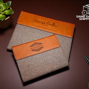 May include: Two document holders with brown leather detailing. The top one has the name "George Heather" and the text "Project Manager." The bottom one displays "Maya Bennett." A succulent plant in a pot and a pen are also visible.