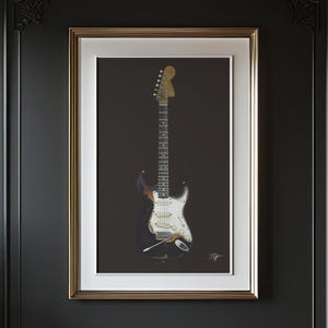 May include: Framed print of an electric guitar. The guitar has a black body with white and brown accents, a white pickguard, and a light brown neck and headstock. The print is in a gold frame with a white mat, set against a dark background.