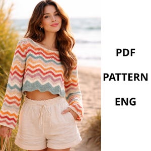 Puede incluir: Un suéter corto de manga larga con un colorido patrón en zigzag en tonos naranja, rojo, amarillo, azul y rosa. El texto "PDF PATTERN ENG" se muestra en el lado derecho de la imagen. La modelo lleva pantalones cortos beige.
