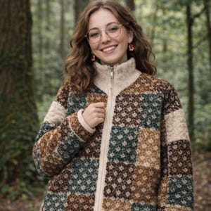 May include: A patterned zip-up cardigan in brown, beige, and teal. The cardigan features a high collar and a full zip. The design is a repeating geometric pattern. The person wearing the cardigan is wearing glasses and earrings.