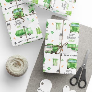 May include: Gift-wrapped presents with a recycling theme. The wrapping paper features green garbage trucks, recycling symbols, and the text "Happy Birthday James!" and "Dump Everything." The gifts are tied with twine and heart-shaped tags.