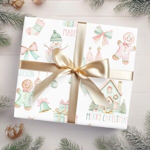 Beautifully wrapped holiday gift with pastel Christmas wrapping paper and gold satin ribbon, includes gingerbread and snowman designs