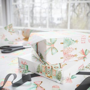 Personalized pastel Christmas wrapping paper for girls featuring gingerbread men, holiday houses, and custom name design