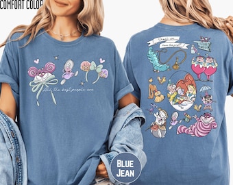 May include: Blue jean-colored t-shirt featuring Alice in Wonderland characters. The front displays a graphic with the Cheshire Cat, butterflies, and text that reads "All the best people are." The back has more characters and the text "Shall we have tea first?"
