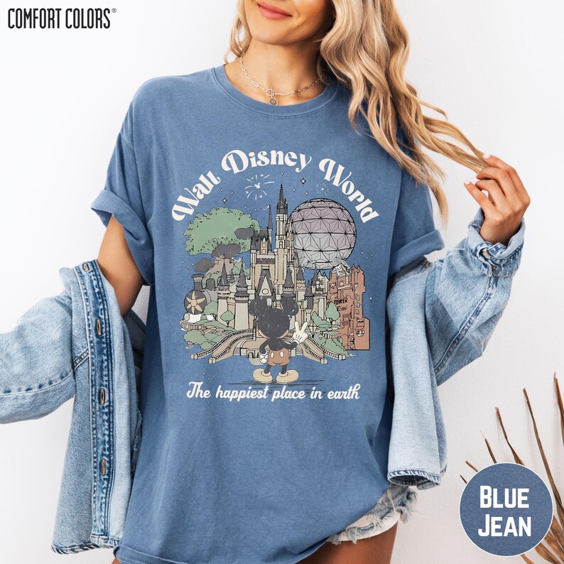 A woman wearing a blue t-shirt with a graphic of Disney World and the text "The happiest place in earth" printed on it.