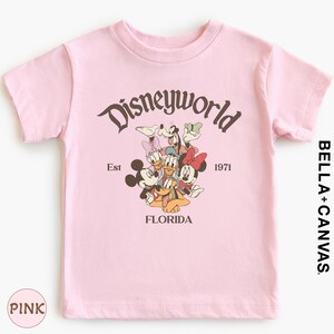 A pink t-shirt with a graphic design featuring Disney characters and text.