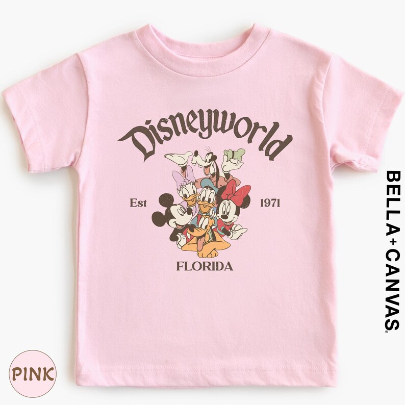 A pink t-shirt with a graphic design featuring Disney characters and text.