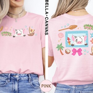 a woman wearing a pink t-shirt with a cartoon pig design and various other colorful illustrations.