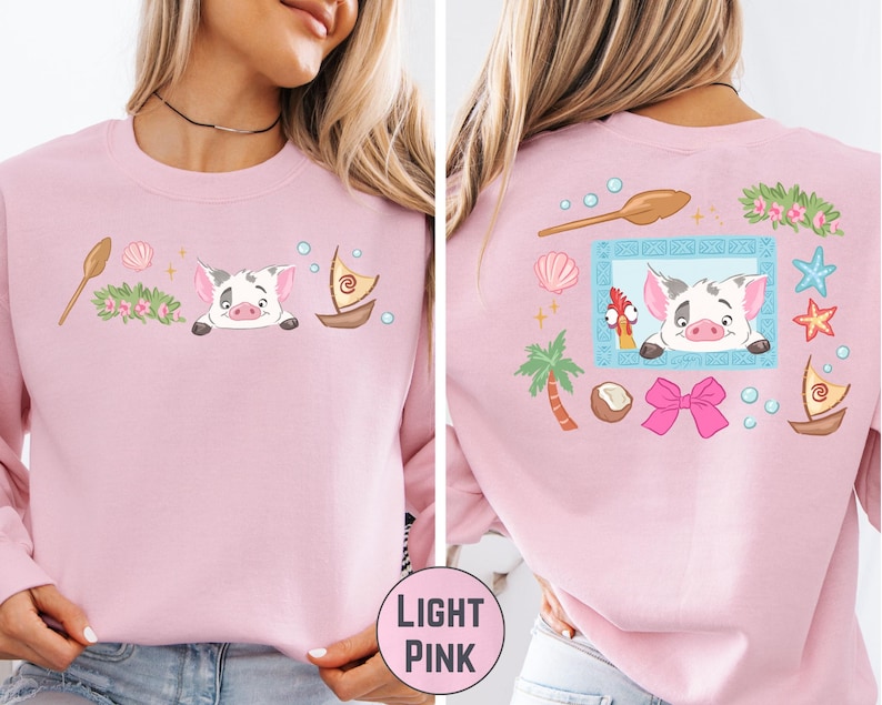 A woman wearing a pink long-sleeved shirt with a cartoon pig design and various other colorful illustrations on the back.