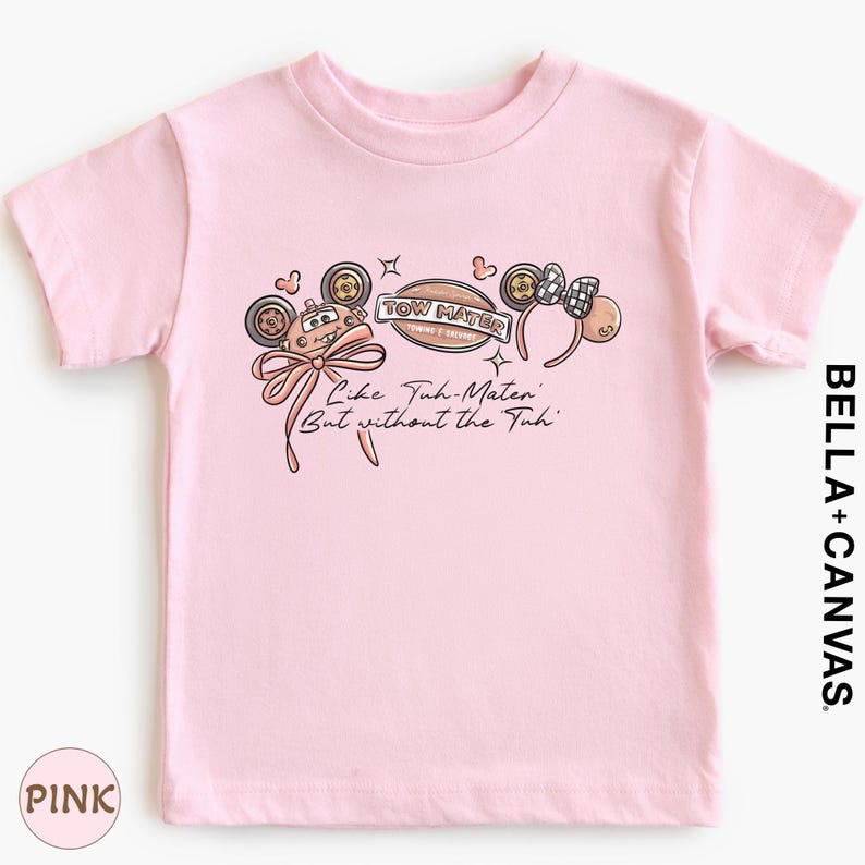 A pink t-shirt with a graphic design featuring a character and the text "Tow Mater" along with the phrase "Like Tum Mater But without the Tui".
