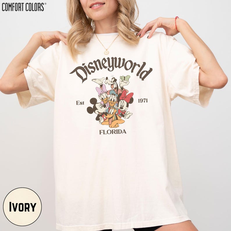 A woman wearing a white t-shirt with a Disneyworld graphic and text printed on it.