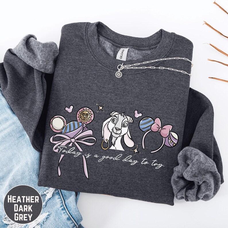 A gray sweatshirt with a graphic design featuring a cartoon character and the text "Today is a good day to try" printed on it.