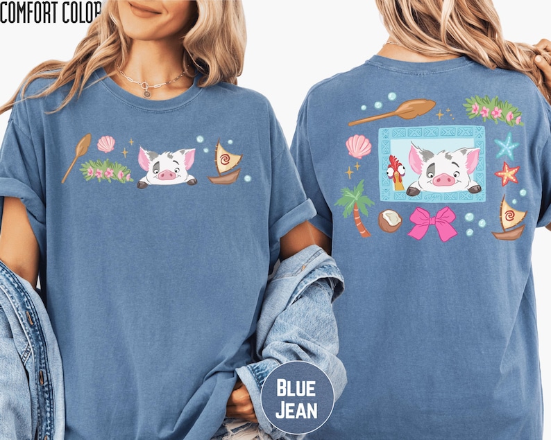 a woman wearing a blue t-shirt with a cartoon pig design and various colorful elements, such as a boat, flowers, and a bow.