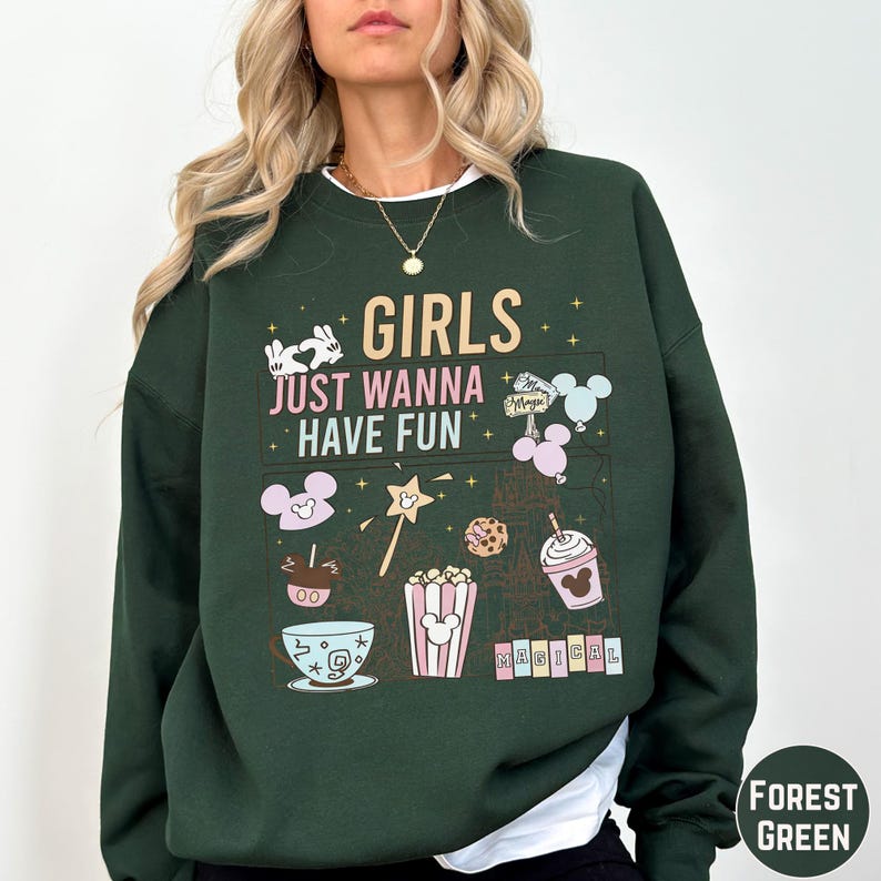 A woman wearing a green sweatshirt with a graphic design featuring various Disney-themed items and text.