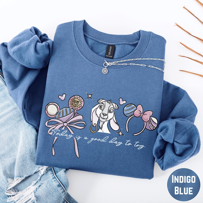 A blue sweatshirt with a cartoon character and text printed on it, along with a necklace and some accessories.
