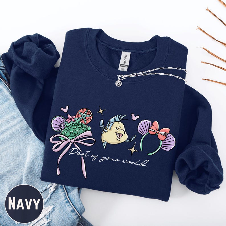 A navy blue sweatshirt with a colorful graphic design featuring a cartoon character and the text "Part of your world" printed on it.