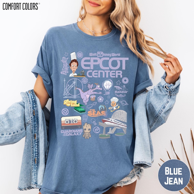 A woman wearing a blue t-shirt with various Disney-themed graphics and text, including a chef, roller coaster, and other iconic landmarks.