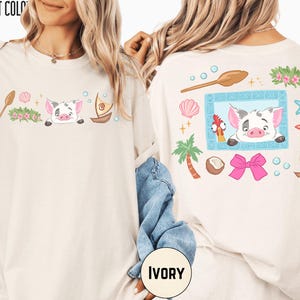 two white t-shirts with colorful and whimsical designs, including a pig, palm tree, starfish, and other tropical elements. The t-shirts are displayed on a person's back, showcasing the vibrant and playful artwork.