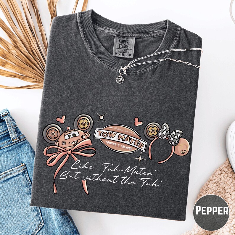 a gray t-shirt with a graphic design, a pair of jeans, and some accessories such as a necklace and a bracelet.