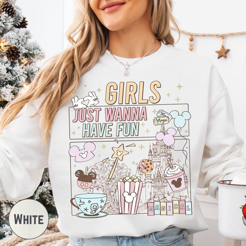 A woman wearing a white sweatshirt with a colorful graphic design featuring various Disney-themed items and text.