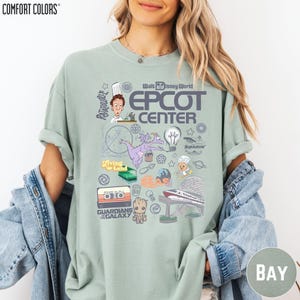 A woman wearing a t-shirt with various Disney-themed graphics and text, including a character, a rocket ship, and other iconic elements associated with the Epcot Center.