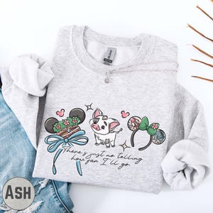 A gray sweatshirt with a graphic design featuring a pig, a pair of headphones, and a ribbon, along with the text "There's just no telling how far I'll go".
